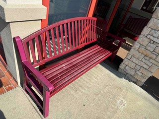 Restaurant bench has a faded and worn finish, with some areas showing wear and discoloration.