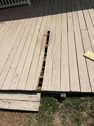 A section of the deck is damaged, with a noticeable gap between the boards and a wood rotten board removed. 
