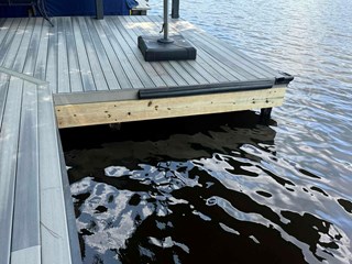 Dock after repairs, the damaged sections have been replaced or fixed, with clean, newer wooden supports visible, giving the dock a more polished and stable appearance.