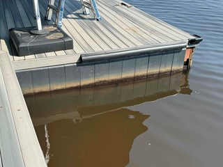 Dock shows visible signs of wear and damage, with the lower portion of the dock's edge worn and stained by water, indicating possible deterioration.