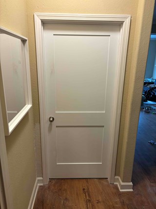 Door area after it has been repaired. The door frame looks newly finished, with the trim intact and the surface smooth.