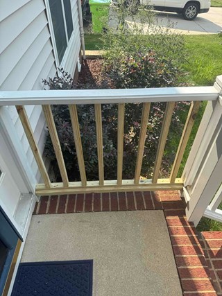 porch railing after the repairs have been made. The broken post has been replaced, and the entire railing is now complete and secure, providing a sturdy and safe structure.