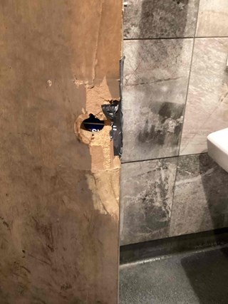 Damaged bar bathroom door with a large hole and a section of the dood. 