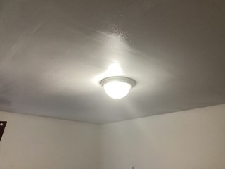 Ceiling after the repairs have been completed. The damaged area has been patched, and the ceiling is now smooth and freshly painted, with no signs of the previous damage.