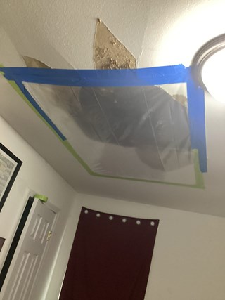 Ceiling with visible water damage, including peeling paint and stains around a hole.