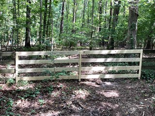 Section of the fence after repairs have been made. The broken part has been replaced with new, well-installed wooden panels.