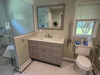 Bathroom after the work has been completed. The wall is now fully repaired, with a new vanity installed, along with a sleek, modern design that includes a new sink, faucet, and mirror.
