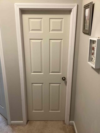 Door frame after the damage has been repaired. The door looks intact, and the frame has been patched and smoothed.