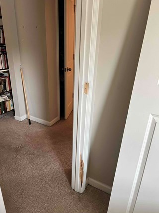 Door frame with visible damage, where the wood is chipped and cracked.