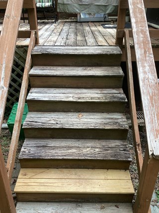 Set of wooden deck stairs that are worn and weathered, with the wood cracking and uneven. The stairs have aged significantly, and some boards are in poor condition, creating an unsafe and unattractive appearance.