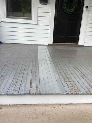 Porch after the boards have been replaced, with fresh paint applied to the wooden planks. 