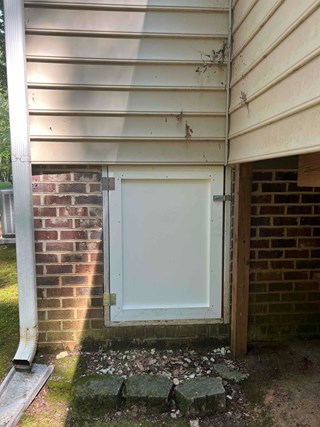 Crawlspace with a newly installed, clean, and solid door. The new door is made of smooth, white material and is properly secured with hinges