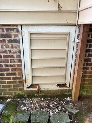 Old crawlspace door that is worn and damaged.