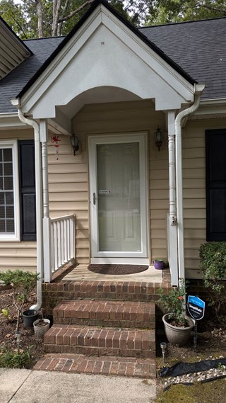 Front entryway with brick steps and a door without any handrails.