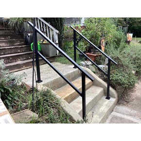 A newly installed set of metal handrails over concrete steps. 