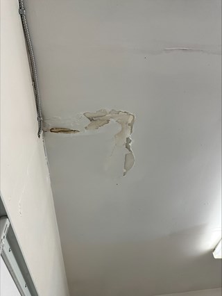 Damaged ceiling with visible water stains and peeling paint from a water leak. 
