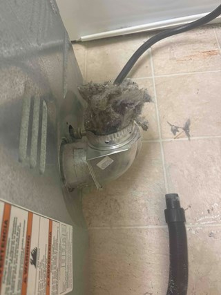 Dryer vent with a buildup of lint around the duct, which can be a potential fire hazard if not regularly cleaned. 