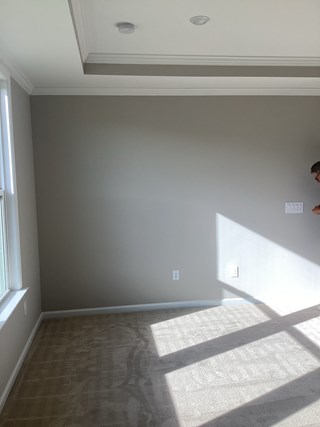 A room with a wall in an Agreeable Gray paint color getting ready to be painted.