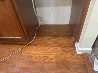 The damaged floorboards have been replaced with wood flooring that matches the surrounding floor. 