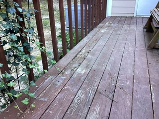 A wooden deck with visible damage, wear, and woodrot.   