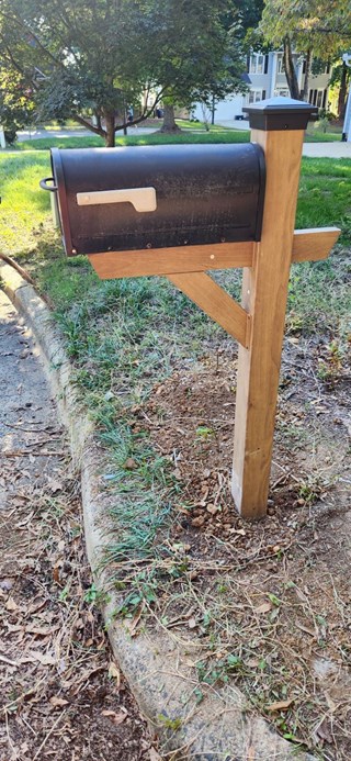 Mailbox newly repaired and securely mounted on a new, sturdy wooden post. 