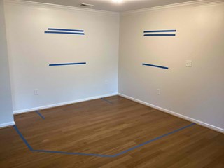  A room with painter's tape applied to the wall in preparation for work, indicating areas where a closet will be built.