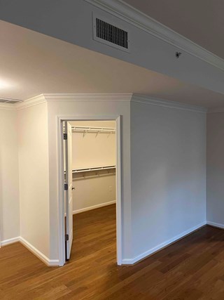 A room with a newly built walk- in closet, the drywall is freshly painted and the shelving is installed. 