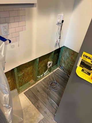 A water heater closet with a section of the wall with exposed studs, where drywall is missing.