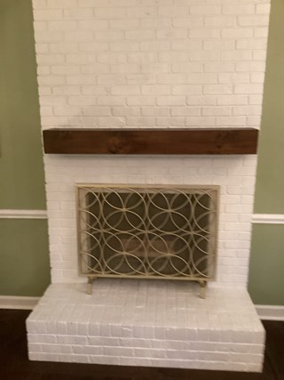 Previously plain white mantel has been replaced with a large, natural wood beam.
