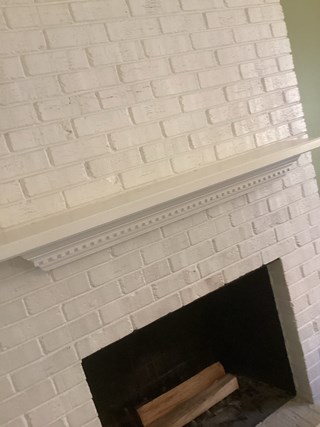 A fireplace with a white-painted brick surround and a simple white mantel above the firebox. 
