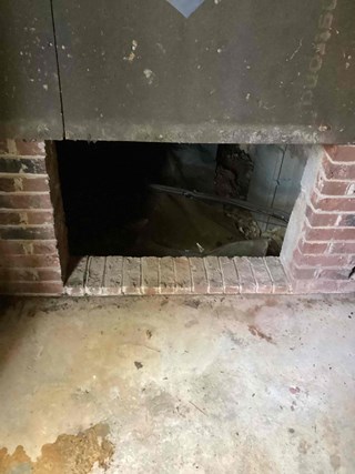 A crawlspace opening in a house, with an exposed opening in the wall. 