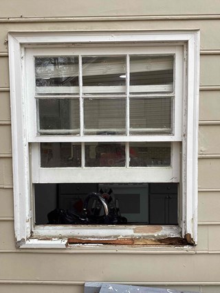 Window with visible damage to the wood frame around the bottom sash. 