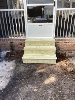 Stairs after the repair work. The old, damaged steps have been replaced with fresh, light-colored wooden steps.