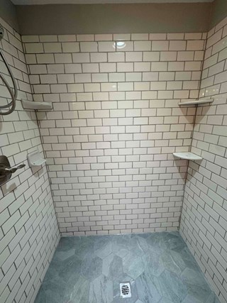 Shower floor fully tile and tile walls freshly grouted. 