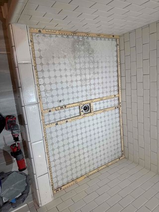 A shower floor with the tile backer board installed and hexagonal tiles dry-laid but not yet fully set.