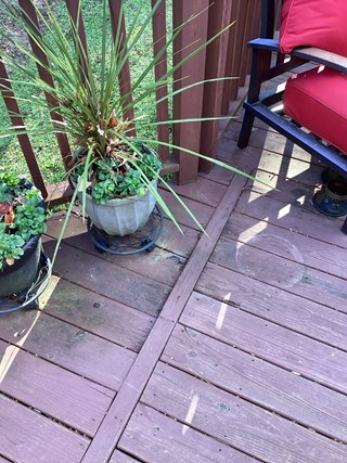 A section of a wooden deck there is noticeable wear on the deck boards.