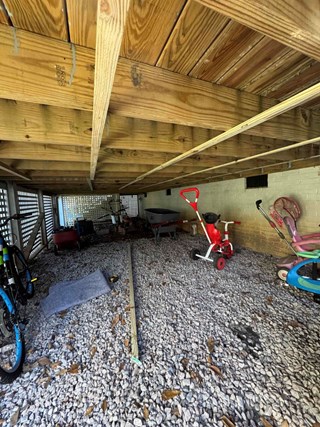 Underside of a deck, showing the support beams and gravel foundation.