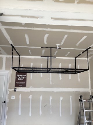 Professional installation of an overhead garage storage system.