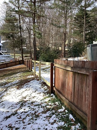 Wood fence installation project. New fence contrasting with older, weathered fence in background.