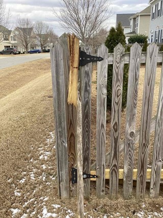 Damaged wood fence gate in need of repair in Riverwood neighborhood of Clayton NC 27527. Residential area with weathered fence.