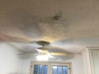 Repaired textured ceiling, seamlessly blending the patched area with the original surface. The ceiling is clean and bright and freshly painted