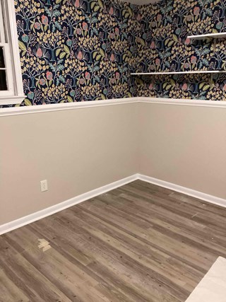 After photo of a successful drywall repair project. The wall is restored to its original condition, with smooth drywall and newly installed baseboards.