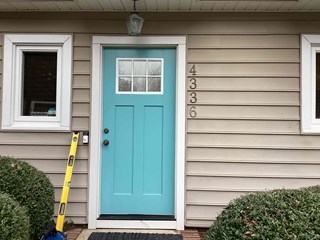  Close-up of a teal front door with multi-paned window, black hardware, and house number 4336. Light tan siding and a "No Soliciting" sign are also visible.