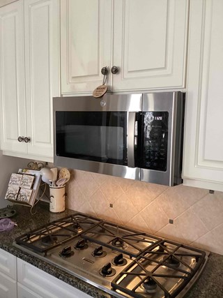 After photo of a new stainless steel GE over-the-range microwave installed in a Cary, NC kitchen, replacing an old GE Spacemaker XL.