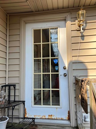 Raleigh, NC, home before door repair: rusted and damaged white exterior door with glass panes. Image shows potential for home improvement and exterior renovation.