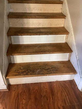  A close-up view of new, white vent covers on wooden stairs in Raleigh, NC 27610, highlighting the completed replacement.