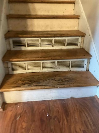  Raleigh, NC 27610, home before vent cover replacement: worn and dirty vent covers on wooden stairs. Image shows need for home improvement and vent cover replacement.