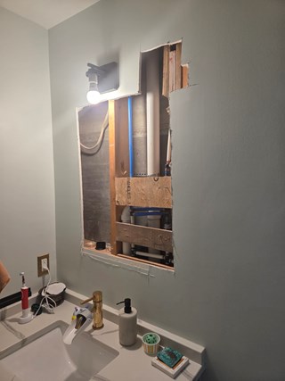 Damaged bathroom drywall with exposed plumbing and framing before repairs in Chapel Hill NC 27514
