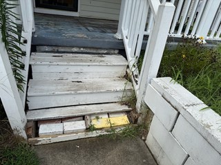 Wooden porch steps and rails with severe deterioration before handyman repair. 