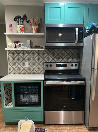 Completed patterned tile backsplash installation between teal cabinets and stainless steel appliances at a Raleigh, NC home by Ace Handyman Service
